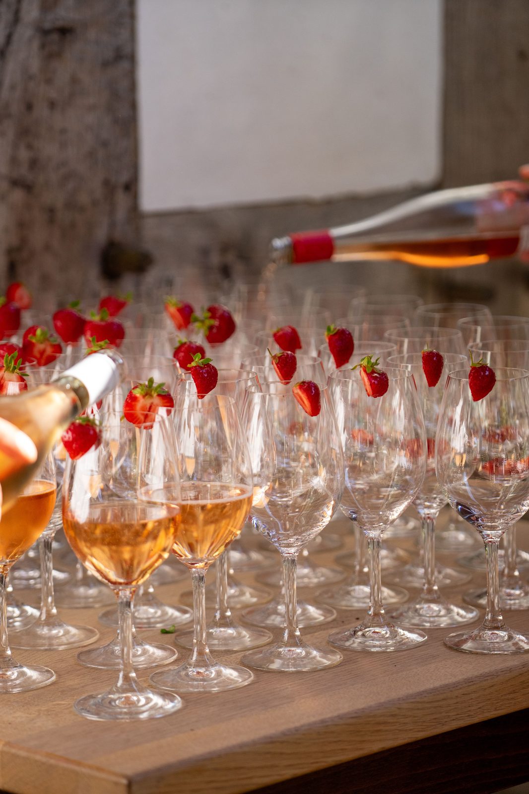 Rosé poured into glasses garnished with strawberries (stock photo)