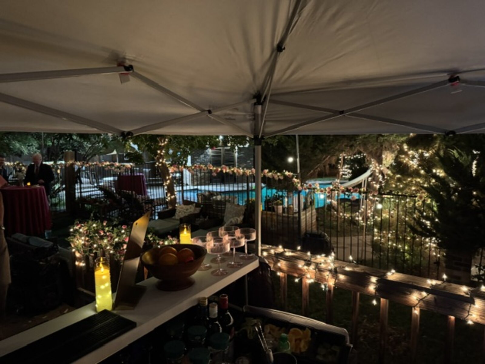 Poolside bar setup strung with lights at dusk